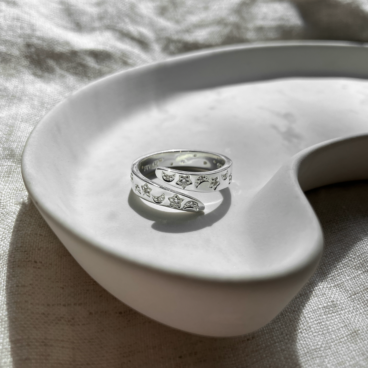 Silver moon and star ring on a white ceramic dish