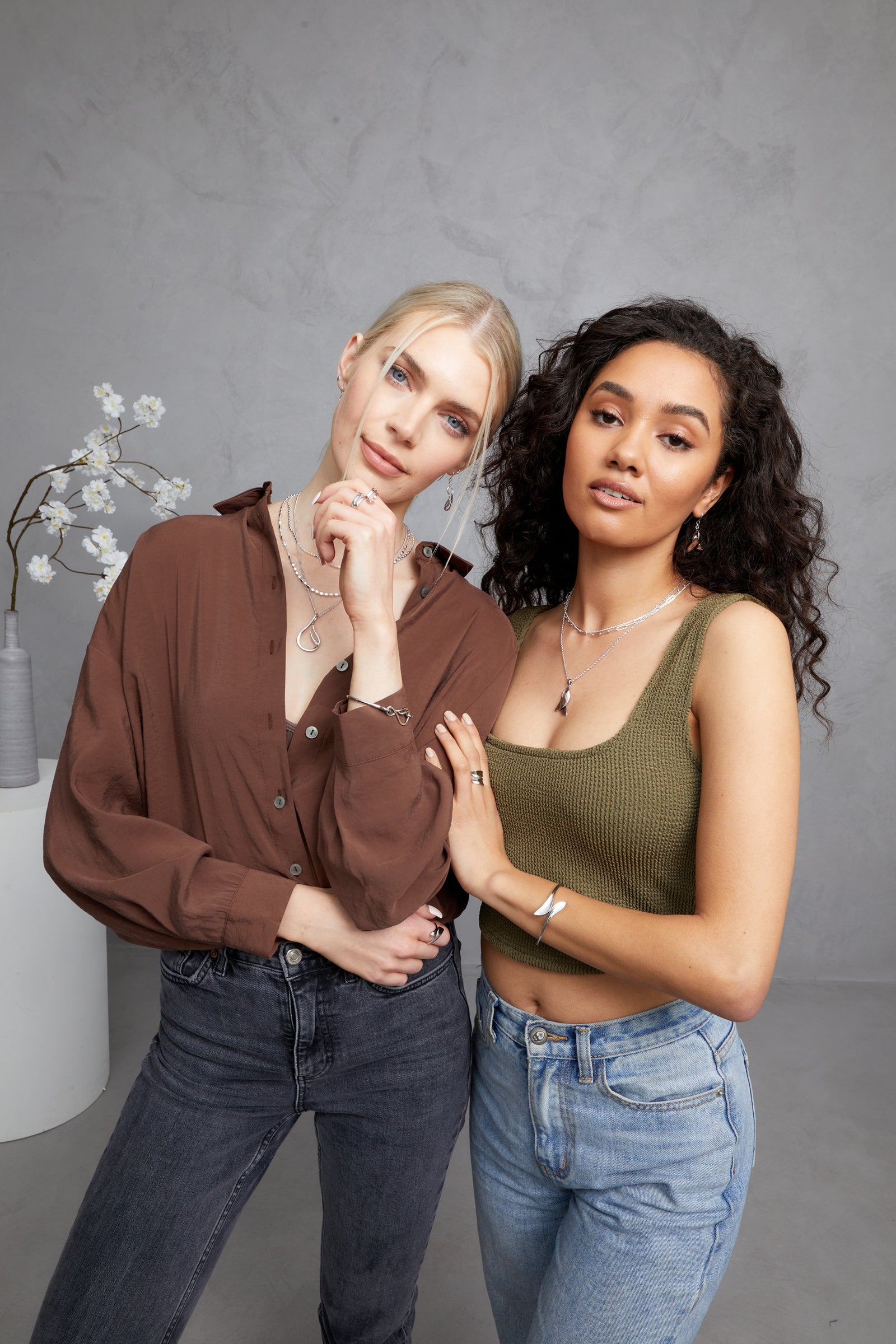 Two models on a FIYAH photoshoot, standing close to one another whilst wearing the FIYAH Silver Wave collection and the FIYAH Silver Flame collection