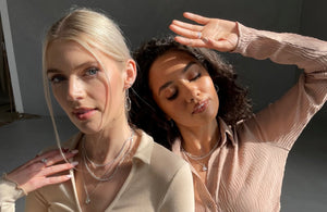 A headshot of two models holding their hands up to their face, whilst wearing a selection of FIYAH jewellery including a FIYAH Clear Quartz Adjustable Healing Ring and a FIYAH Clear Quartz Adjustable Healing Necklace