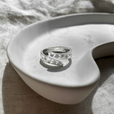 Silver moon and star ring on a white ceramic dish